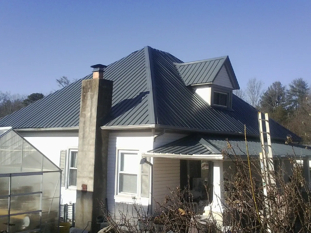 Dark blue standing seam metal roof on a white farmhouse with dormer — Slate & Tile Roof Repair by Roofing Brothers in New Prague
