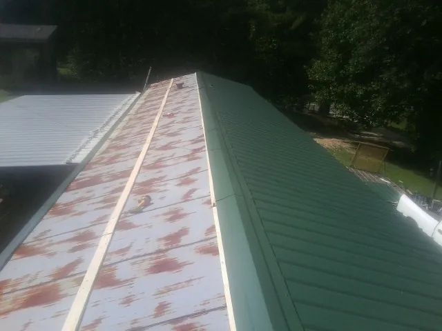 Old rusted panels beside newly installed green metal roofing — Wind Damage Roof Repair by Roofing Brothers in New Prague