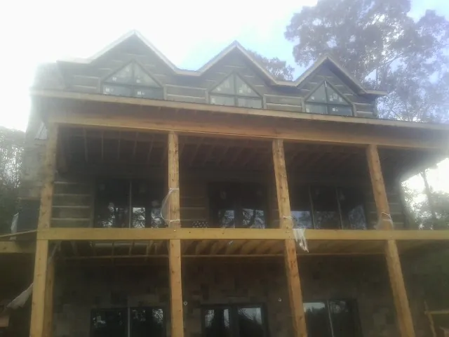 Dormers and porch framing on a large log home under construction — Roof Coating work by our crew in New Prague