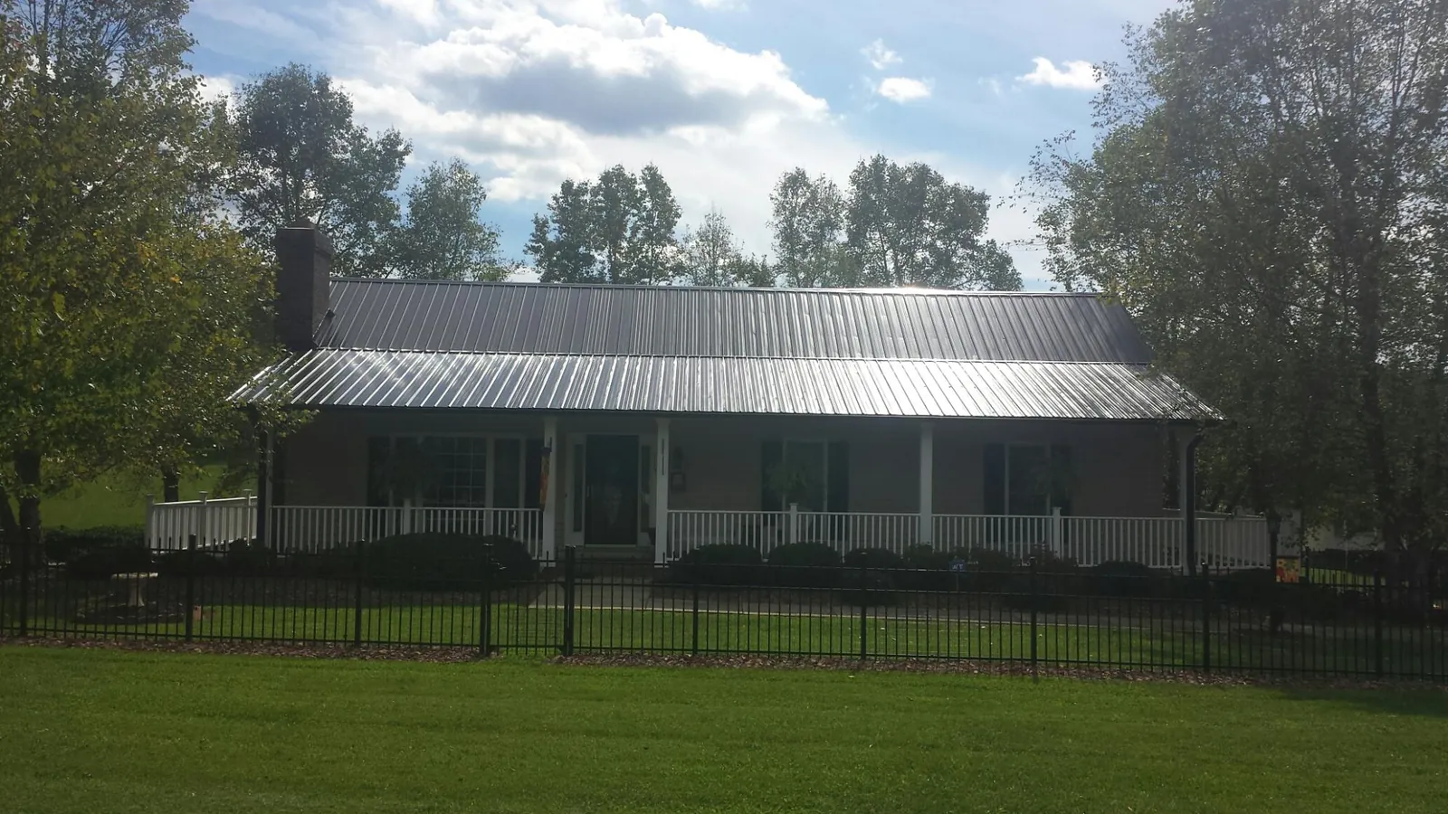 Gray metal roof on a brick ranch with a full width front porch — Gutter Guard Installation work by our crew in New Prague