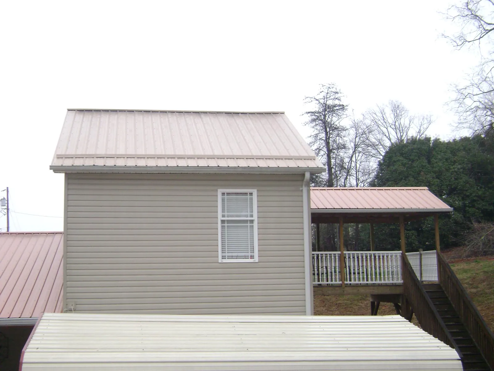 Tan metal roofs on a two story addition and attached porch, from a Roof Replacement job in New Prague