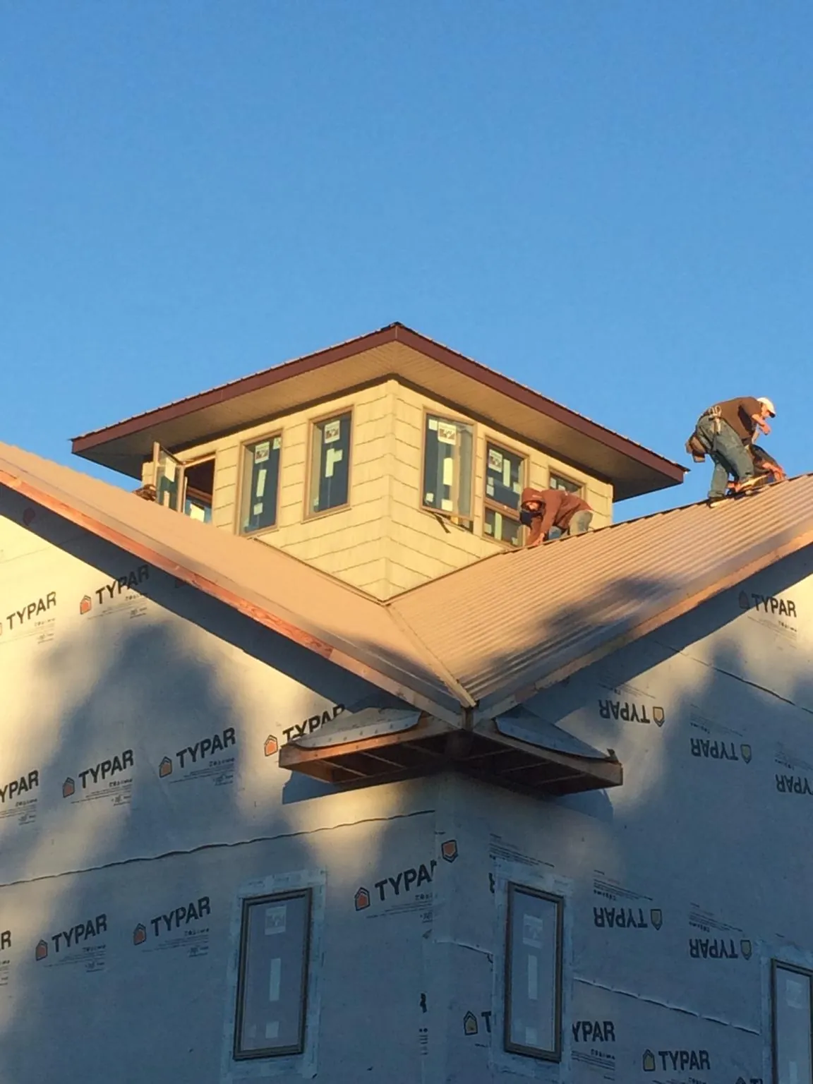 Roofers working around a rooftop cupola on a new metal roof at sunset — Roof Waterproofing in New Prague by Roofing Brothers